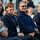 2015 Australian International Airshow and Aerospace & Defence Exposition A group of people seated in what appears to be a VIP section at an outdoor event, laughing and smiling. Several individuals are wearing dark navy jackets and lanyards with VIP credentials. The atmosphere appears festive and celebratory.