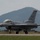 2015 Australian International Airshow and Aerospace & Defence Exposition A U.S. Air Force F-16 Fighting Falcon jet fighter is taxiing on a runway at an airfield. The aircraft bears tail code 'WW' and serial number 'AF 92-912', indicating it belongs to the 35th Fighter Wing based at Misawa Air Base, Japan. A mountainous, hilly landscape is visible in the background under an overcast sky.