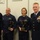 Coast Guard Sector Buffalo 2014 EPOY and REPOY ceremony Four U.S. Coast Guard personnel pose for a formal photo, with two members holding eagle-topped trophies or awards. The setting appears to be an indoor facility with whiteboards visible in the background displaying text related to 'Risk Assessment/Planning' and 'Prevention'. The rightmost individual wears a formal dress uniform with extensive medal ribbons, suggesting senior rank.