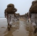 Marines and sailors hike along the beach
