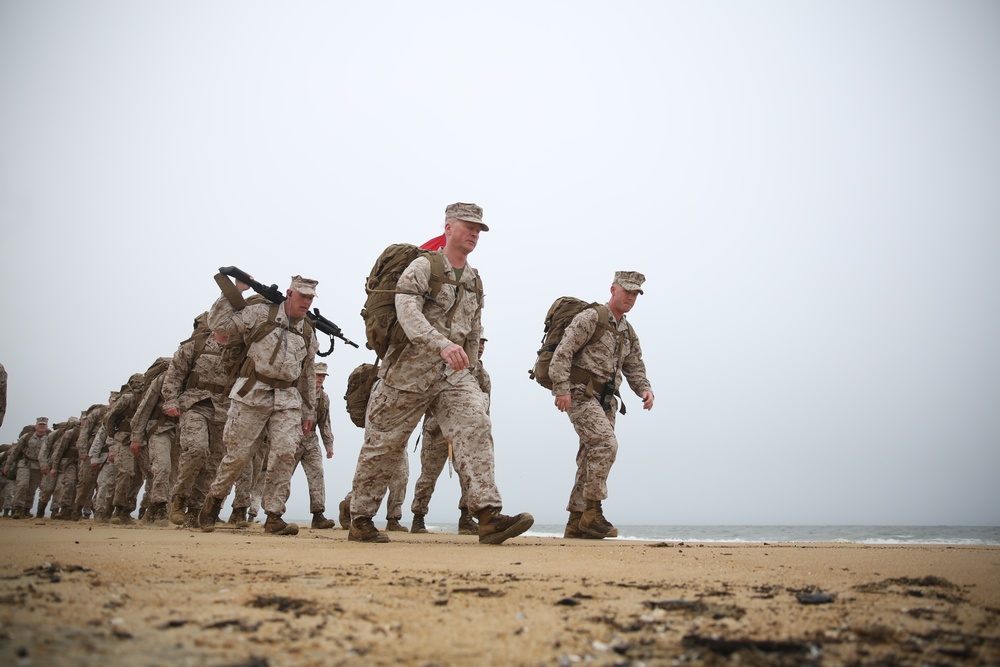 Marines conduct beach hike enhancing unit morale, maintain combat readiness.