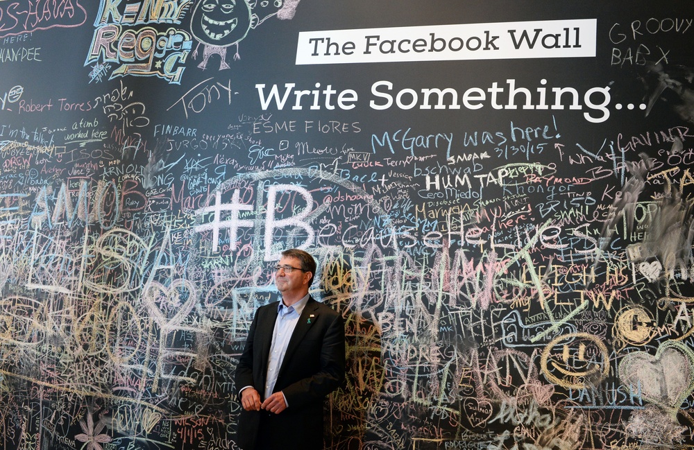 Secretary of Defense Ash Carter stands in front of the Facebook Wall during his recent trip to their headquarters