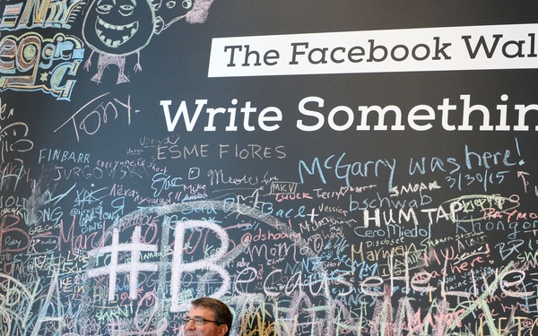 Secretary of Defense Ash Carter stands in front of the Facebook Wall during his recent trip to their headquarters