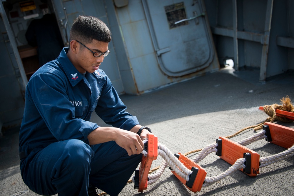 Sailor works on pilot's ladder