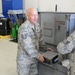 Tech. Sgt. Anthony Ballard and Tech. Sgt. Ryan Williams display a new module for a generator to be installed into a portable generator May 18