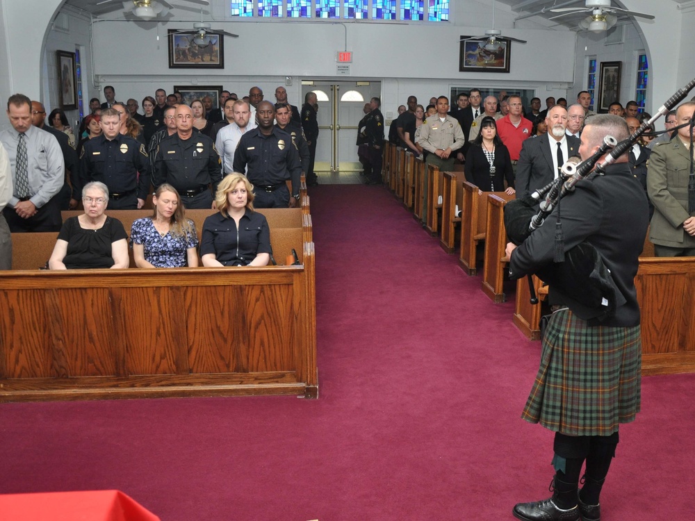 Bagpipes render Amazing Grace for a full chapel during memorial services for Lt. Levi Baker