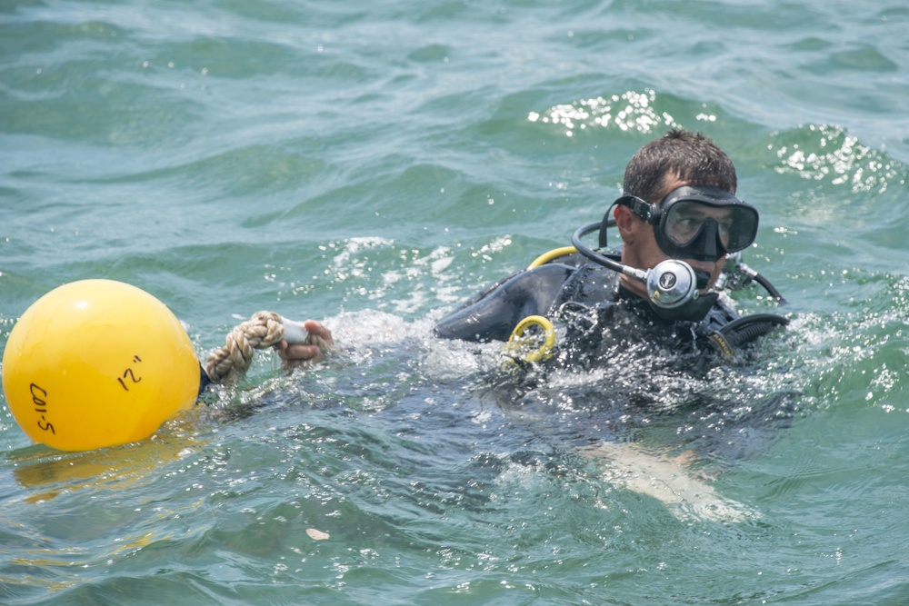 Navy diver moves buoy during POW/MIA recovery mission