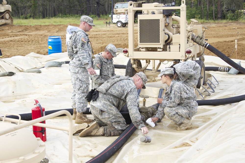 Soldiers clear water away from fuel line couplings