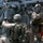 Maritime Raid Force, 26th MEU conducts VBSS training The image shows multiple armed military or special operations personnel in tactical gear positioned on what appears to be the deck of a naval vessel. They are in active tactical stances, with weapons raised and aimed. The personnel are wearing desert/tan camouflage uniforms, helmets, body armor, and communications equipment.