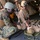 Maritime Raid Force, 26th MEU conducts VBSS training Military personnel in full combat gear are attending to a simulated or actual casualty lying on a stretcher in what appears to be the interior of a naval vessel or military facility. Two service members are kneeling and standing over the prone individual, appearing to administer or assess medical aid. Additional armed personnel in the background suggest this may be a training exercise or post-operation medical response.