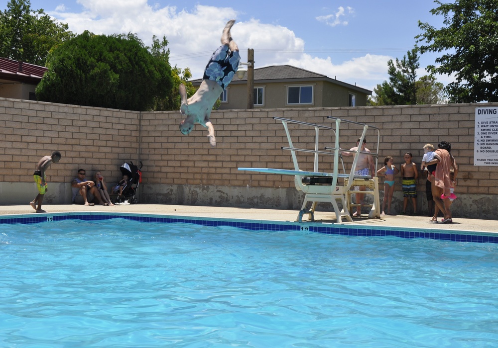 Capt. W. Adam Hemme, company commander for Fleet Services Division, shows the kids how it is done on the diving board during the All American BBQ at the Oasis Pool and Water Park aboard Marine Corps Logistics Base Barstow, Calif., July 4