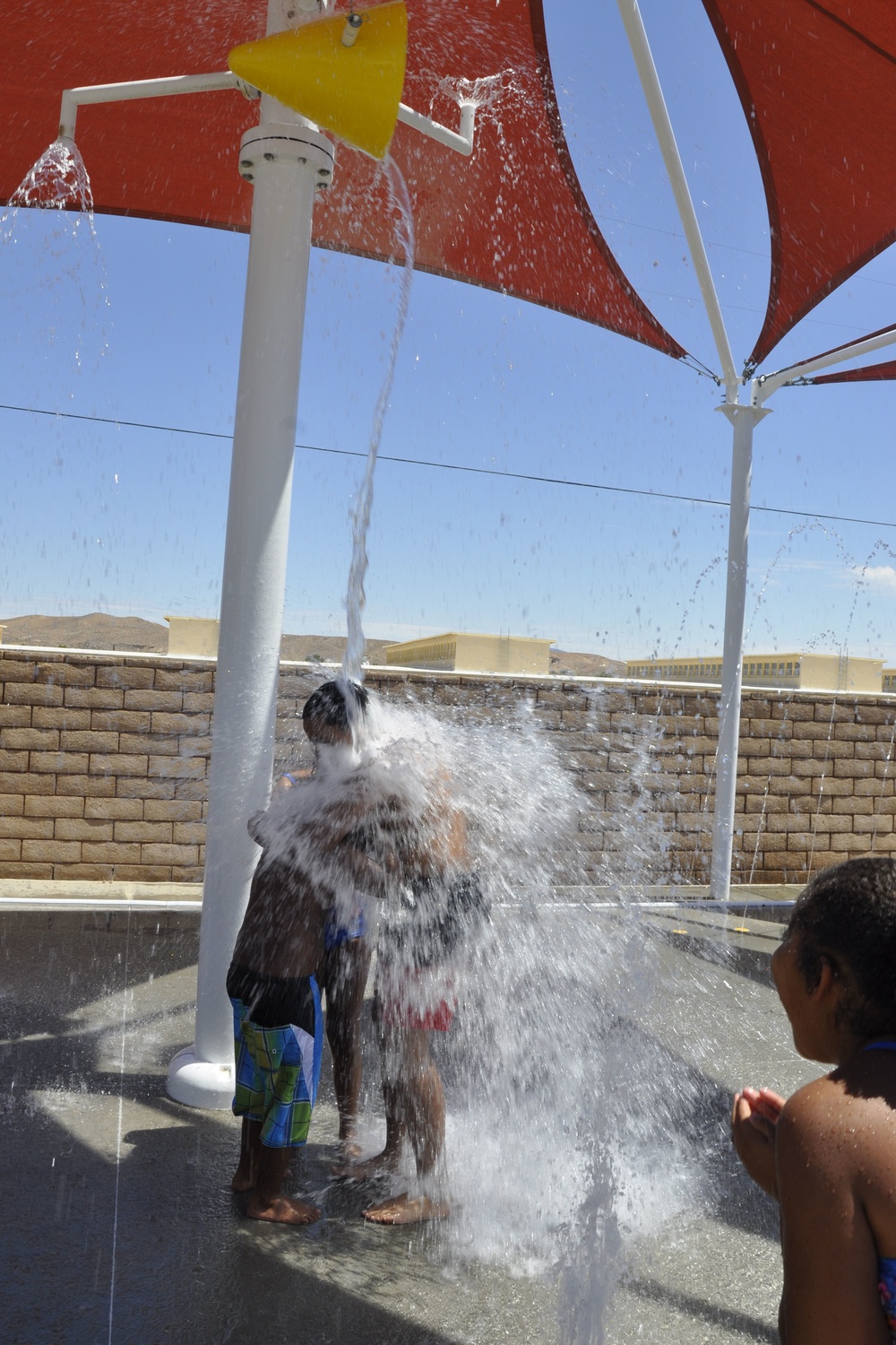 Children of military service members huddle together in anticipation of a bucket of water about to douse them at the Oasis Pool and Water Park aboard Marine Corps Logistics Base Barstow, Calif., during the All American BBQ, July 4