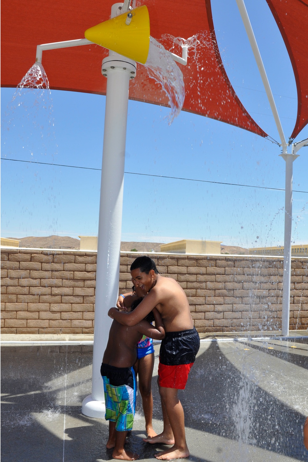 Children of military service members huddle together in anticipation of a bucket of water about to douse them at the Oasis Pool and Water Park aboard Marine Corps Logistics Base Barstow, Calif., during the All American BBQ, July 4