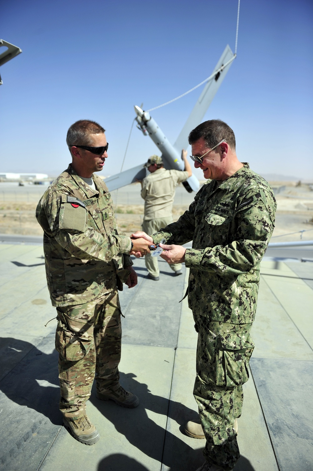 NOSC Whidbey Island Sailor present US Navy Rear Adm. Luke McCollum, vice commander, U.S. Naval Forces Central Command, with ScanEagle Guardian Eight Site patch at Kandahar Airfield June 25, 2015