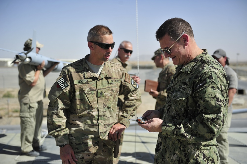 NOSC Whidbey Island Sailor present U.S. Navy Rear Adm. Luke McCollum, vice commander, US Naval Forces Central Command, with ScanEagle Guardian Eight Site patch at Kandahar Airfield June 25, 2015