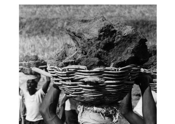 A Bengali laborer totes a load of earth on a river bank project