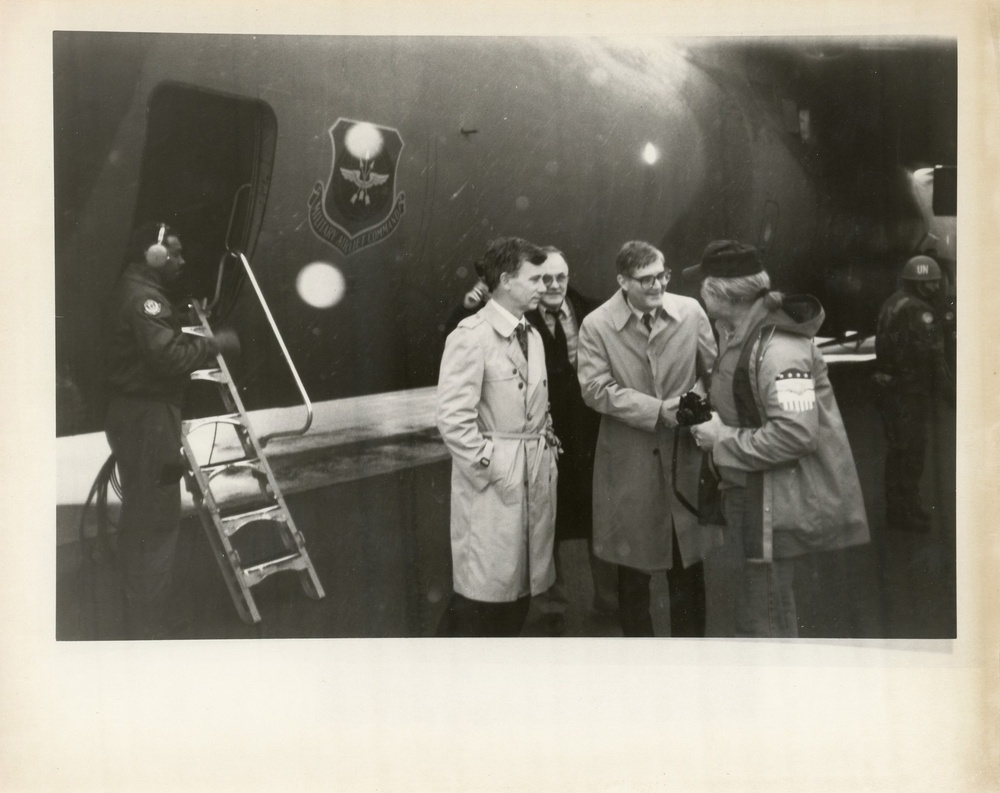 Two men and woman in front of aircraft carrier