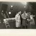 Two men and woman in front of aircraft carrier