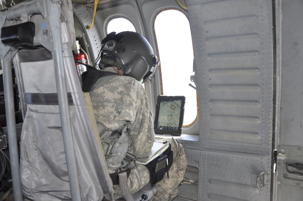 Capt. Adam Kennedy, company commander for Alpha Company, 2916th Aviation Battalion with the U.S. Army, National Training Center Fort Irwin, stationed at Barstow-Daggett Airport, observse progress of the flight in a Black Hawk aircraft, using maps