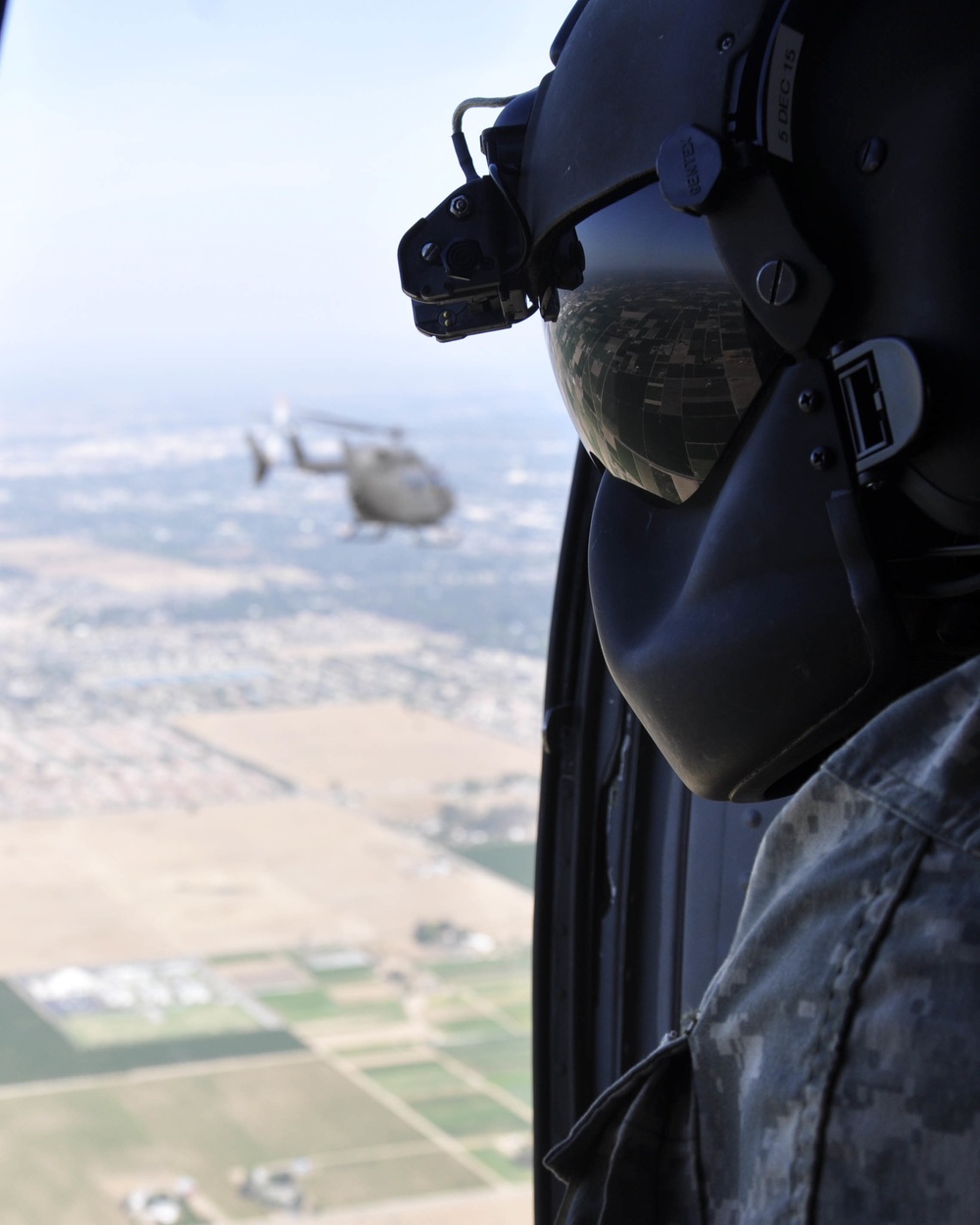 Spc. Kevin Bowers, crew chief with A Company, 2916th Aviation Battalion with U.S. Army National Training Center Fort Irwin, stationed at Barstow-Daggett Airport, watches out the window of a Black Hawk helicopter as they escort a Lakota aircraft