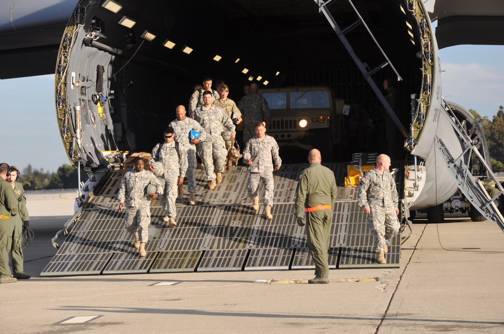 Soldiers disembark C-5 and off-load HMMWVs