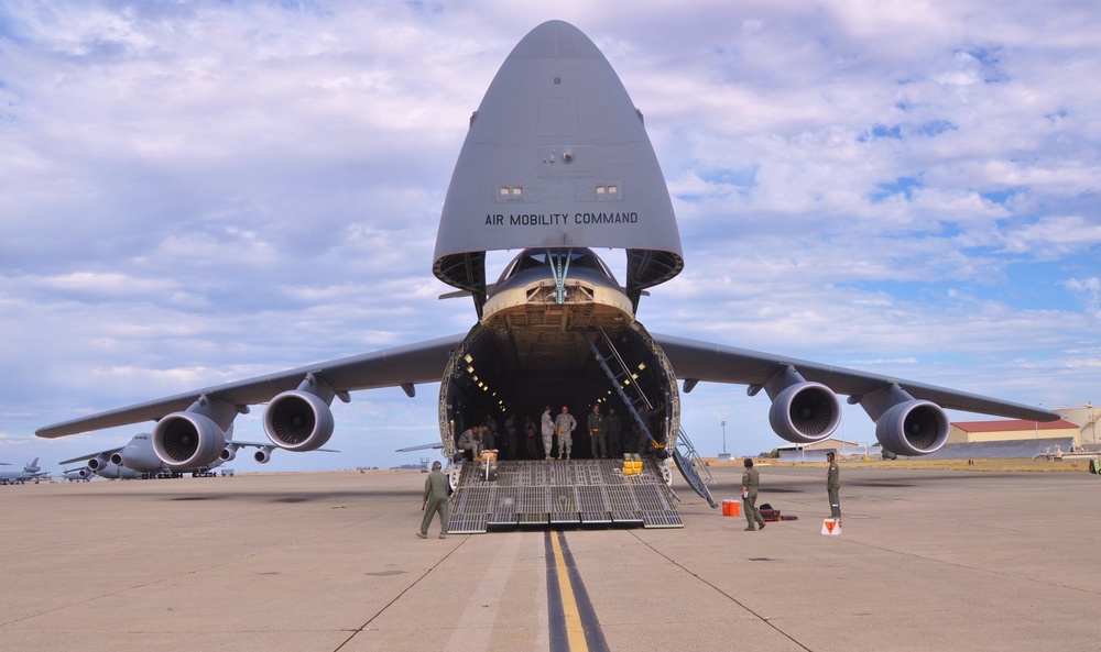 Soldiers and Airmen prepare to load HMMWVs aboard C-5