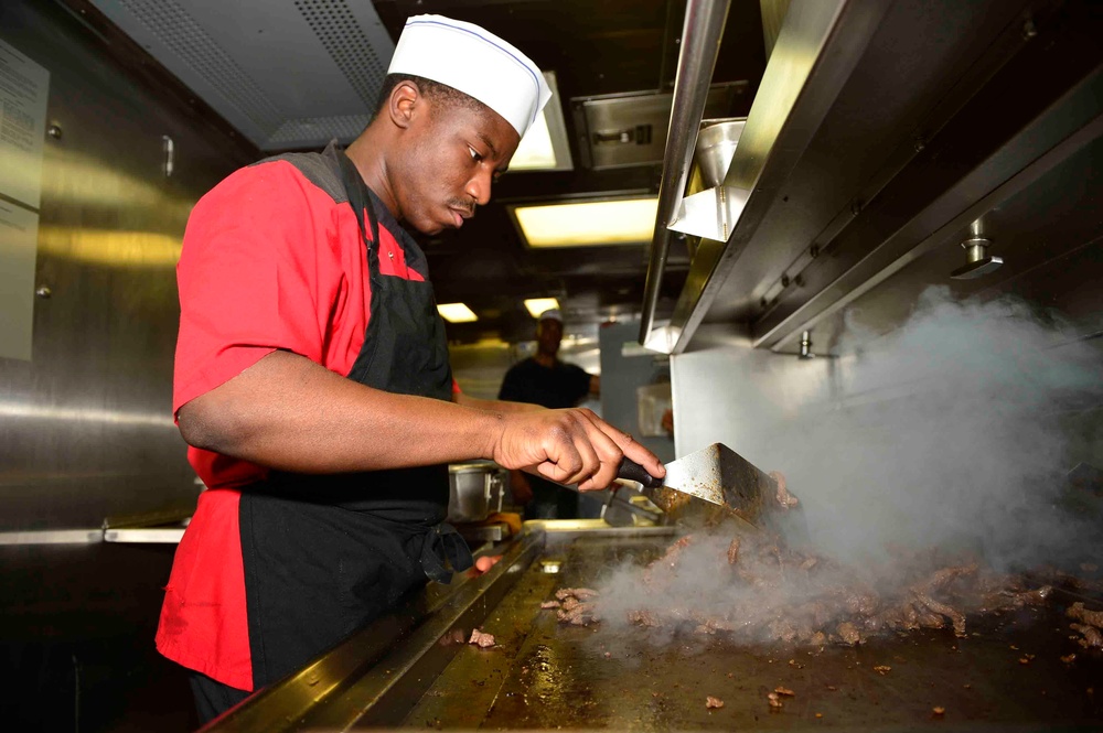 USS Forrest Sherman Sailor prepares food in the galley