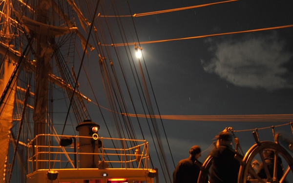 Coast Guard Cutter sails under a full moon