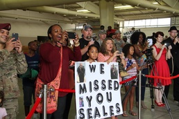 Family and friends of the returning Soldiers of Blue Team, 1st Sustainment Command (Theater) cheer and display signs at Pope Army Airfield, Aug. 24 as they return from a nine-month deployment to Kuwait