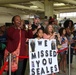 Family and friends of the returning Soldiers of Blue Team, 1st Sustainment Command (Theater) cheer and display signs at Pope Army Airfield, Aug. 24 as they return from a nine-month deployment to Kuwait