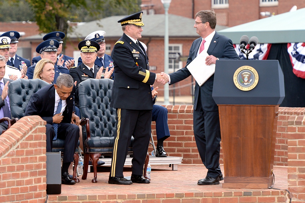 Secretary of defense shakes hands with outgoing chairman of the Joint Chiefs of Staff