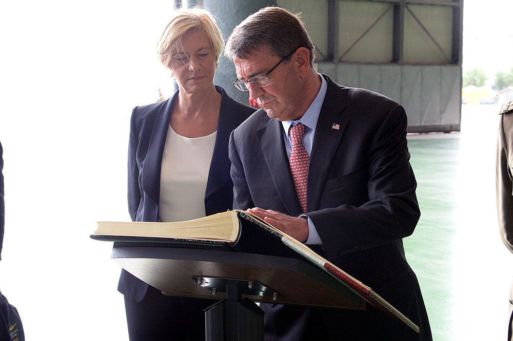 Secretary of defense signs a guest book while Italian Defense Minister Roberta Pinotti looks over his shoulder