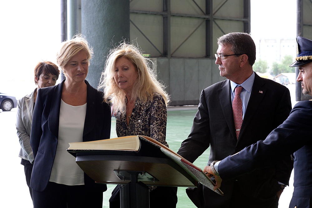 Secretary of defense looks on as Italian Defense Minister Roberta Pinotti listens to what he wrote