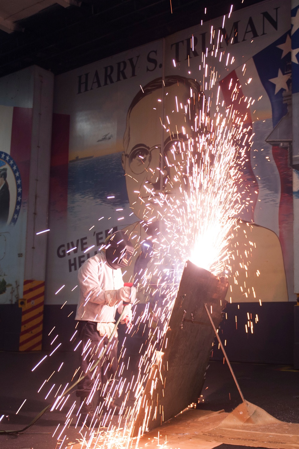 USS Harry S. Truman Sailor cuts a sheet of metal