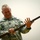 A U.S. Army soldier with the name tape 'MORGAN' is holding and examining what appears to be a historical or antique musket/rifle. He is wearing the Army Combat Uniform (ACU) with visible rank insignia consistent with a Senior Non-Commissioned Officer. He appears to be smiling while inspecting the firearm.