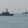 The image shows two naval warships operating in open sea under hazy atmospheric conditions. Both vessels appear to be guided-missile destroyers based on their silhouettes, with a third, much smaller vessel visible on the distant horizon. The ships appear to be underway or at slow speed in calm waters.