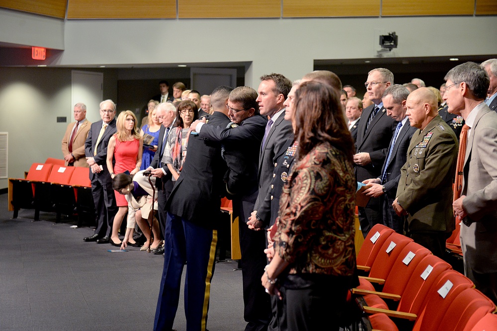 Secretary of defense and retired Army Capt. Florent Groberg share an embrace during his Medal of Honor Hall of Heroes induction ceremony