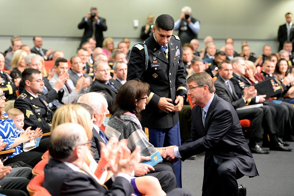 Secretary of defense shakes hands with retired Army Capt. Florent Groberg's family members at the Medal of Honor Hall of Heroes induction ceremony