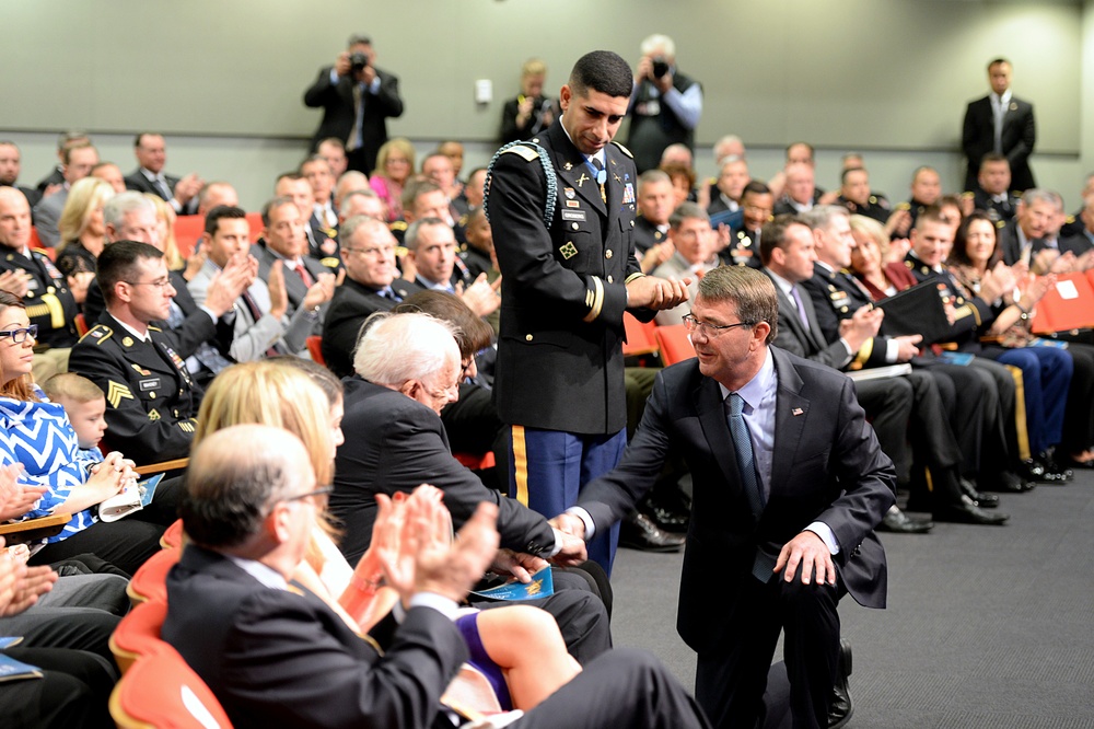 Secretary of defense shakes hands with retired Army Capt. Florent Groberg's family members at the Medal of Honor Hall of Heroes induction ceremony