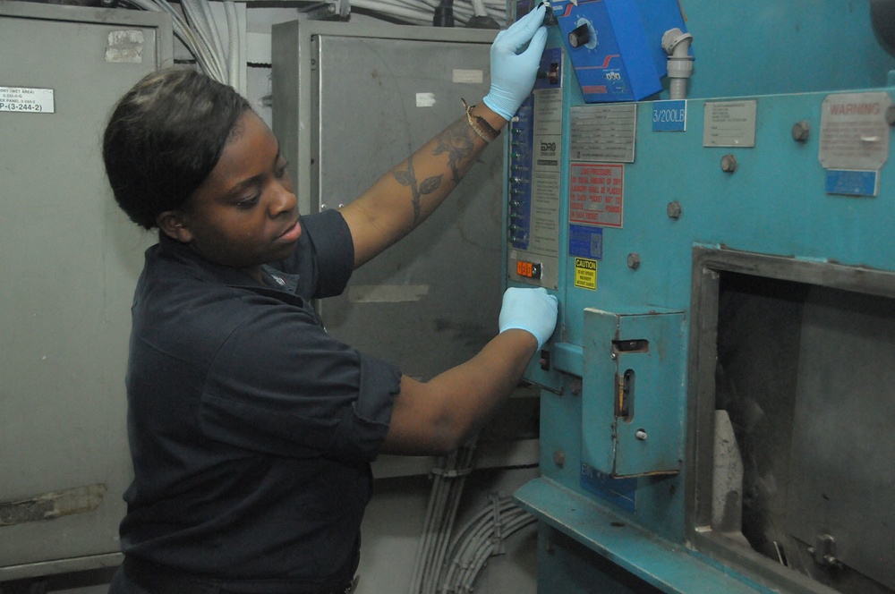 USS George Washington Sailor operates an industrial laundry machine