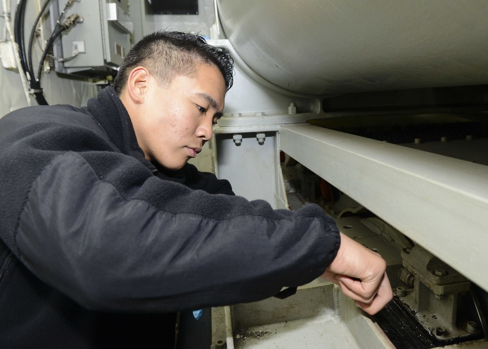 Nimitz Sailor performs arresting gear maintenance