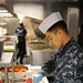 Nimitz Sailor cuts tomatoes on mess decks