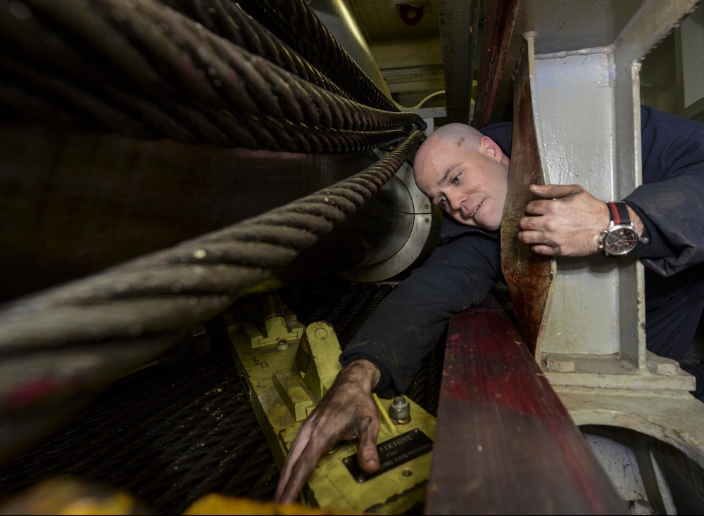 Nimitz Sailor performs maintenance on arresting gear