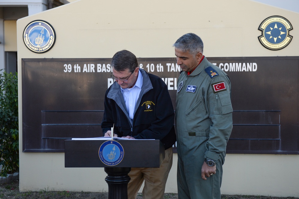 Secretary of defense signs a guest book as Brigadier General Bekir Ercan Van, 10th Base Commander Incirlik Air Base, Turkey looks on.