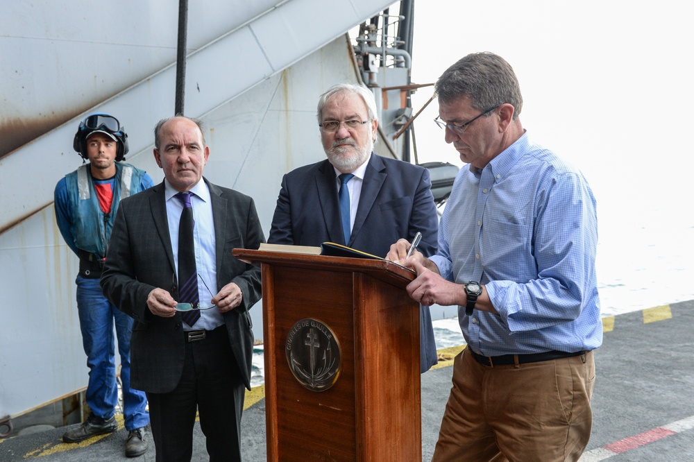 Secretary of defense signs the guestbook aboard the flagship of the French Navy, the Charles De Gaulle