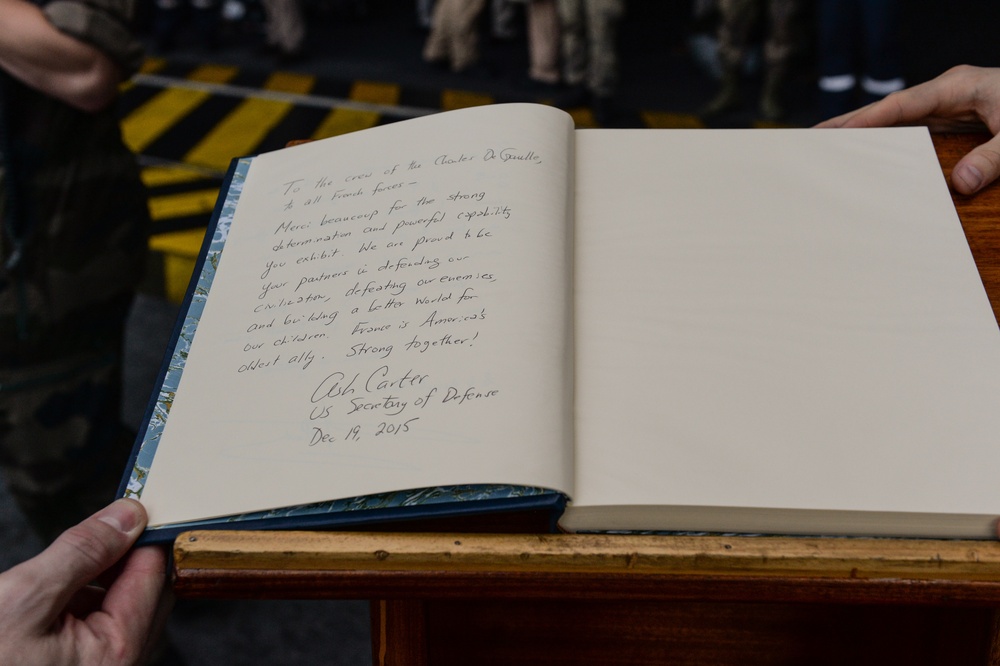 Secretary of defense signs the guestbook aboard the flagship of the French Navy, the Charles De Gaulle