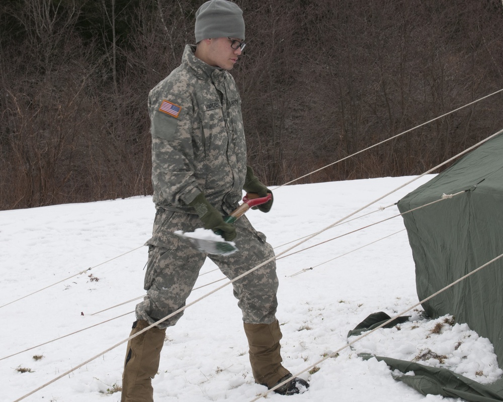 Soldier shovels snow on tent to secure it