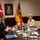 German, Turkish leadership meet to discuss coalition forces partnerships A formal bilateral meeting is taking place at a conference table between delegations, with the Turkish flag and German flag visible in the background alongside a framed portrait on the wall. Participants are seated on opposite sides of the table, which is set with water bottles, tea cups, and a floral centerpiece. The setting appears to be an official government or military meeting room.