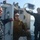USNS Wheeler Performs Demonstration, Holds Tour for Military Officials Three military personnel are aboard a naval patrol vessel on open water. Two individuals are wearing U.S. Navy digital camouflage (NWU Type I) uniforms, while one person in the center is wearing an olive/coyote brown jacket with camouflage pants. They appear to be observing or surveying the surrounding water area from the boat.