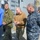 USNS Wheeler Performs Demonstration, Holds Tour for Military Officials Three senior military personnel are engaged in conversation on the deck of what appears to be a naval vessel. The individuals are wearing different military uniforms including Marine Corps MARPAT camouflage, a tan/coyote fleece, and Navy NWU (Naval Working Uniform) digital blue camouflage. Additional personnel in uniform are visible in the background.